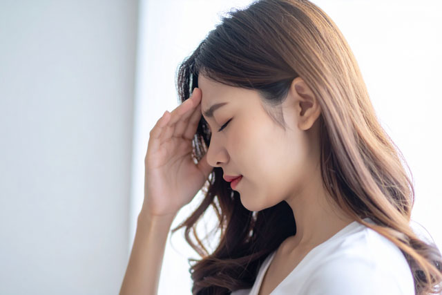 頭を手で押さえる女性